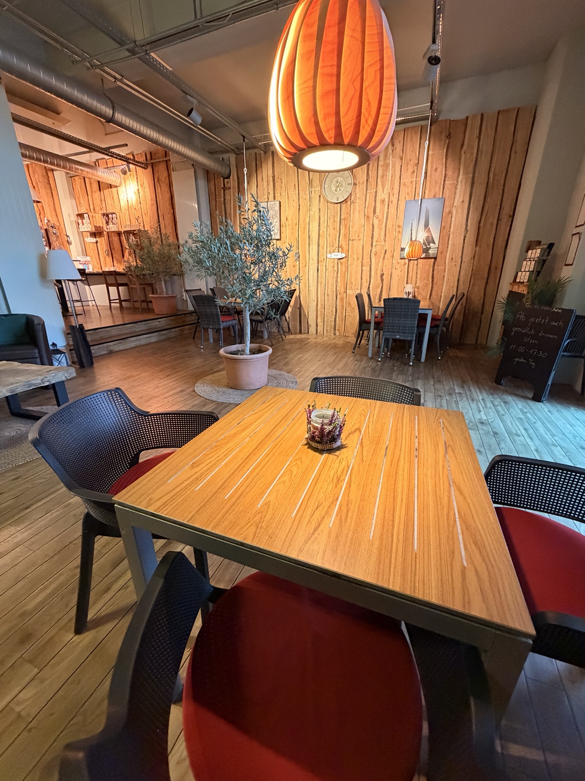 Holztisch unter einer warm leuchtenden Lampe im Café